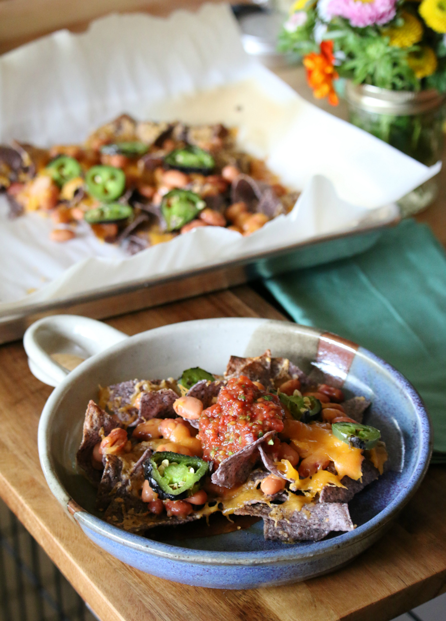 Blue Corn Nachos with roasted jalapeno, pinto beans, cheddar cheese and topped with Fire Roasted Jalapeno Salsa. 